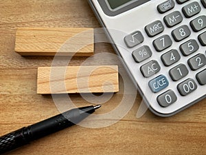 Top view of blank wooden blocks, pen and calculator with wooden desk background.