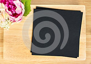 Top view of Blank wooden plate with black paper and flower pot on table