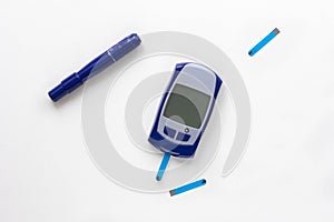 Top view of blood glucose meter, lancet and test strip in it on the white background