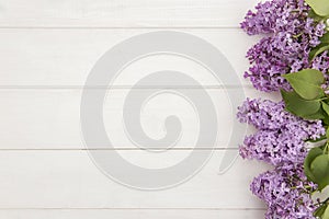 Top view of blooming lilac branches designed as one side frame on white wooden background