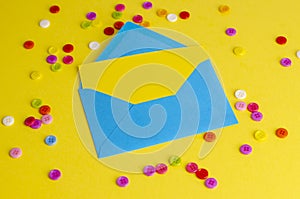 Top view of blue envelope,yellow blank card and colorful buttons.