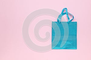 Top view of a blue gift bag on a pink background