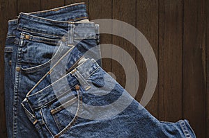Top view, Blue jeans stacked on a dark brown wooden background, The right copy space