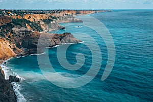 Top view of blue sea water with white waves and stones.