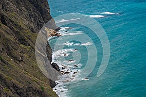 Top view of blue sea water with white waves and stones.