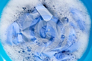 Top view of blue shirt soak in powder detergent water dissolution