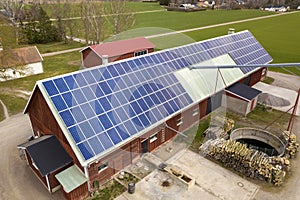 Top view of blue solar photo voltaic panels system on wooden building, barn or house roof. Renewable ecological green energy