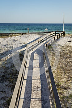 Top view of a board walk over the white sand with grass heading to the beach at Destin, Florida