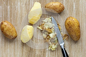 Top view of boiled potatoes in jackets and scrubbed on the wooden background