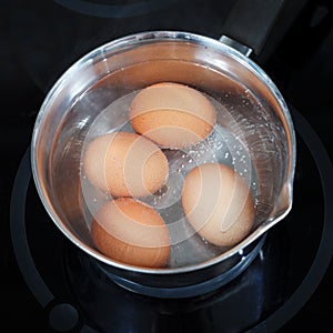 Top view of boiling chicken eggs in metal pot