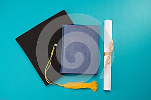 Top view of book graduation mortarboard and diploma on blue education