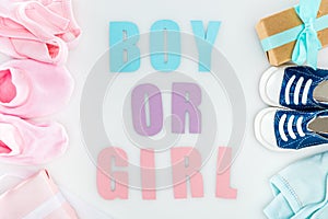 Top view of booties and sneakers, boy or girl lettering, gift boxes and bonnets.