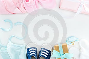 Top view of booties and sneakers, pacifier, gift boxes and bonnets on white background.