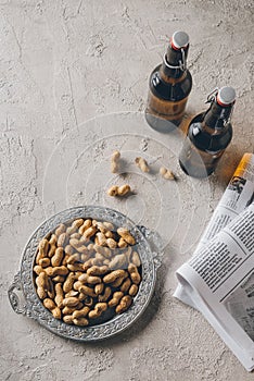 top view of bottles of beer peanuts and newspapers arranged