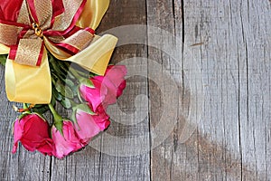 Top view of bouquet of red roses with ribbon on old wooden board background. Right space for message. romance love card or wedding