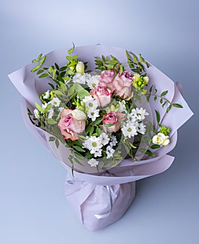 Top view of a bouquet of roses and green twigs on a blue background.