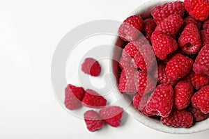 Top view of bowl with delicious ripe raspberries on white background