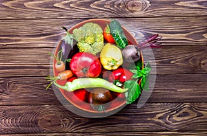 Top view bowl with different Fresh Farm Vegetables on the dark wooden background. Harvest. Food or Healthy diet concept.Vegetarian