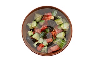 Top view on a bowl of homemade vegetable salad with tomatoes, cucumbers and black olives, isolated on white background