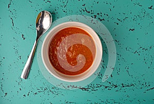 Top view of a bowl of Indian cottage cheese and tomato sauce with a spoon beside the bowl