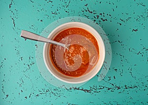 Top view of a bowl of Indian cottage cheese with tomato sauce with a spoon in the bowl