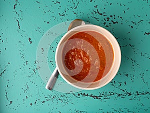 Top view of a bowl of Indian cottage cheese with tomato sauce with a spoon under the lip of the bowl