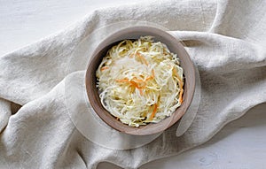 Top view of bowl of sauerkraut with cabbage on towel