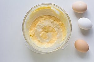 Top view of bowl with thickened custard cream and eggs on the white background photo
