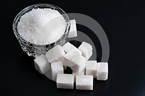 Top view on a Bowl with white granulated and refined sugar on bl