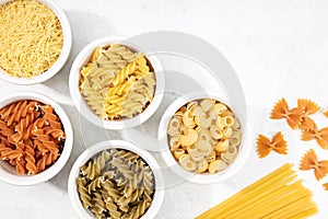 Top view of bowls with assorted uncooked pasta. Copy space