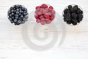 Top view, bowls containing berries: blueberries, blackberries, raspberries. Healthy eating and dieting. From above, overhead.