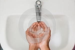 Top view of a boy cupped soapy hand against washbasin