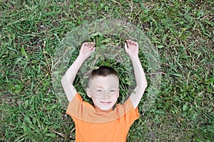 Top view of boy lying on the grass at park having fun. Child relax with smiling. carefree concept