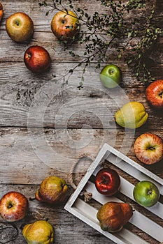 top view of branch, wooden box, pears and apples