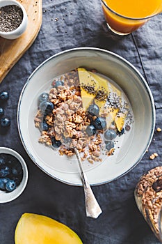 Top view of breakfast table for one, crunchy granola with fresh berries and cream or milk.