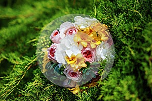 Top view of bridal bouquet with white, yellow and rose flowers on grass in summer wedding day. Outdoor wedding decor. Idea for