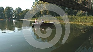 Top view on bride and groom sitting in an white boat floating out of the tree covering and in to the lake