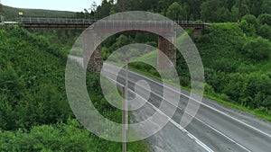 Top view of bridge with road under it in forest. Scene. Old bridge over rural highway in wooded area. Bridge with roads