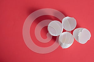 Broken eggshells on a vibrant red background. Top view
