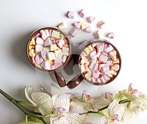 Top view of brown cups of hot cocoa with marshmallows in heart shape on white background