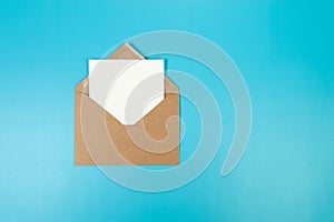 Top view of brown Kraft envelope, white card on blue background.