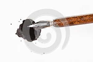 Top view of brown nib pen over black ink blot