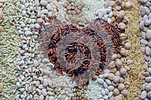 Top view of brown and rice berry seed in heart shape on variety natural cereal and grain seed stripe background