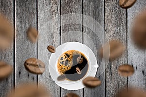 Top view of brown roasted coffee beans falling and flying to coffee cup.Represent breakfast for energy and freshness concept