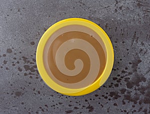 Top view of brown turkey gravy in a small yellow bowl on a gray background