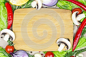 Top view of brown wooden cutting board with summer vegetables and champignon mushroom on table background.