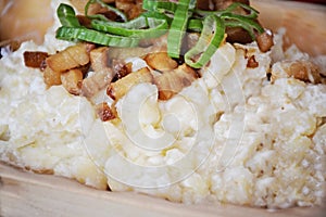 Top view on bryndzove halusky with smoked bacon and fresh green onion served in wooden plate - slovak national food. Healthy and