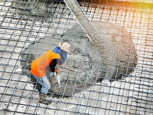 Top view of builders in orange shirt pouring concrete works on the construction site