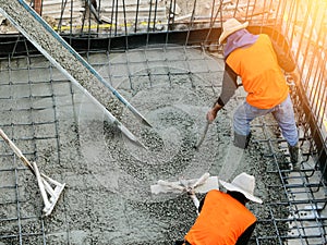 Top view of builders in orange shirt pouring concrete works on the construction site