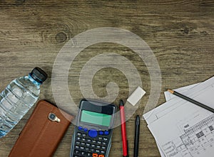 Top view building plan,stationery and calculator on grey wooden background
